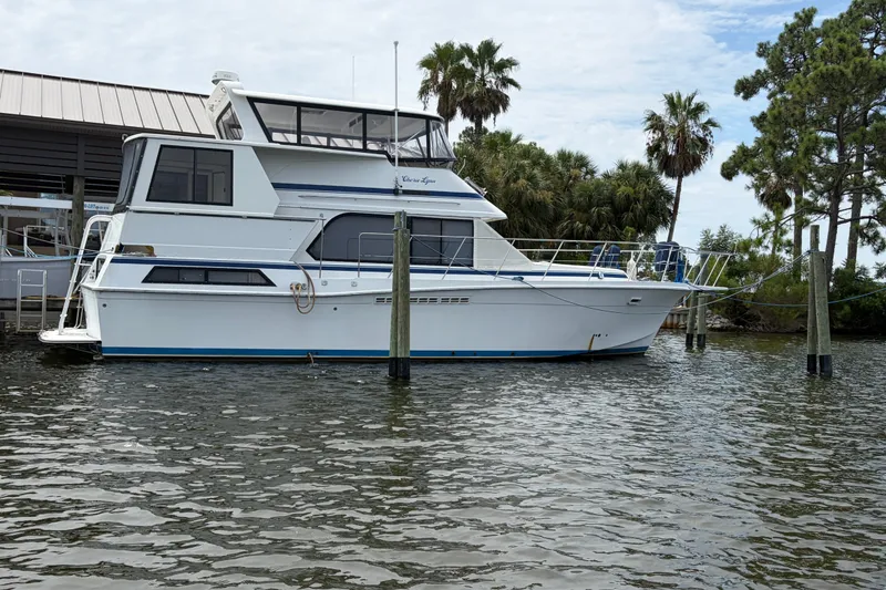 Slide: The Image of 1989 Chris-Craft 427 Catalina yacht docked near palm trees and calm waters. - 2