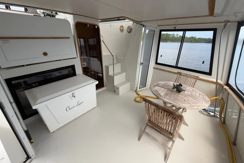 Slide: The Image of 1989 Chris-Craft 427 Catalina yacht interior with wooden table, chairs, and scenic water view. - 12