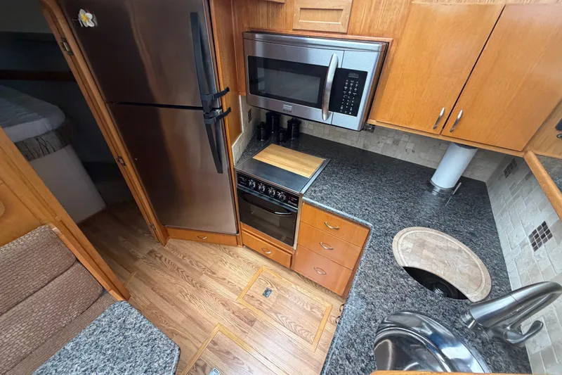 Slide: The Image of 1989 Chris-Craft 427 Catalina kitchen with stainless appliances and wood cabinetry. - 33