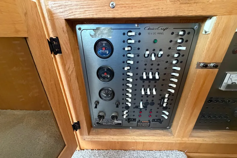 Slide: The Image of 1989 Chris-Craft 427 Catalina control panel with switches and gauges in wooden cabinet. - 53