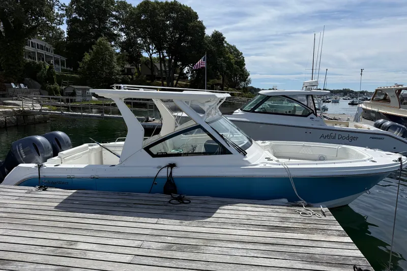 Slide: The Image of 2023 Edgewater 262CX Crossover boat docked at a marina, featuring dual engines. - 3