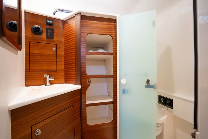 Slide: The Image of 2025 Pursuit OS 405 Offshore yacht bathroom with wood cabinetry and frosted glass door. - 66
