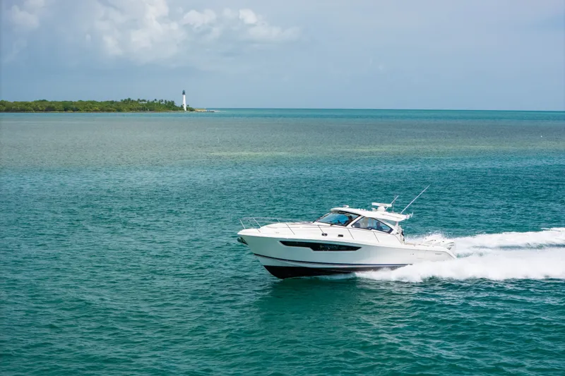Slide: The Image of 2025 Pursuit OS 405 Offshore boat cruising on open water near a lighthouse. - 15