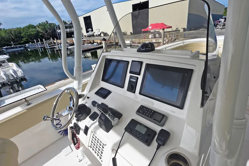 Slide: The Image of 2015 Intrepid 327 Center Console boat dashboard with modern navigation equipment at a marina. - 4