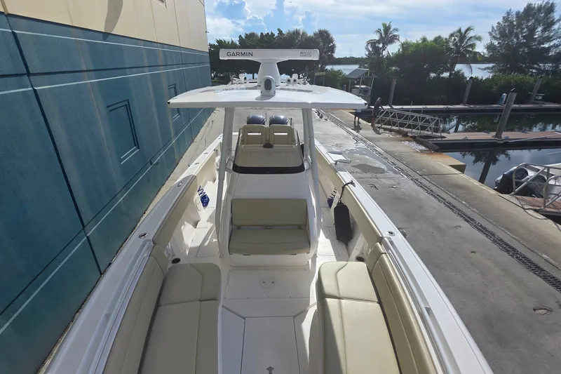 Slide: The Image of 2015 Intrepid 327 Center Console boat docked, featuring spacious seating and Garmin equipment. - 16