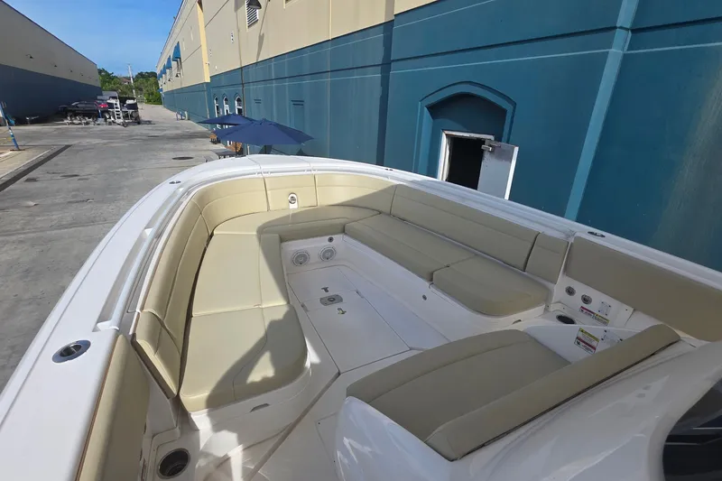 Slide: The Image of 2015 Intrepid 327 Center Console boat with spacious seating, docked near a blue building. - 13