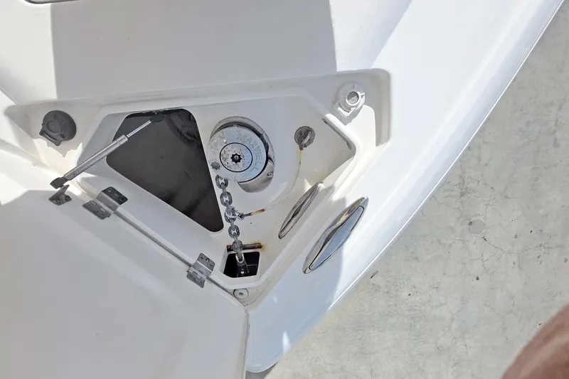 Slide: The Image of Anchor compartment of 2015 Intrepid 327 Center Console boat, featuring chain and latch mechanism. - 35