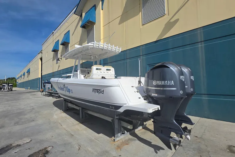 Slide: The Image of 2015 Intrepid 327 Center Console boat with Yamaha engines, parked near a building. - 4