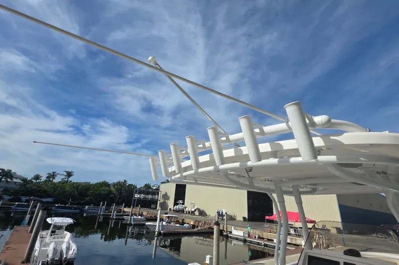 Slide: The Image of 2015 Intrepid 327 Center Console boat with rod holders, docked under a clear blue sky. - 28