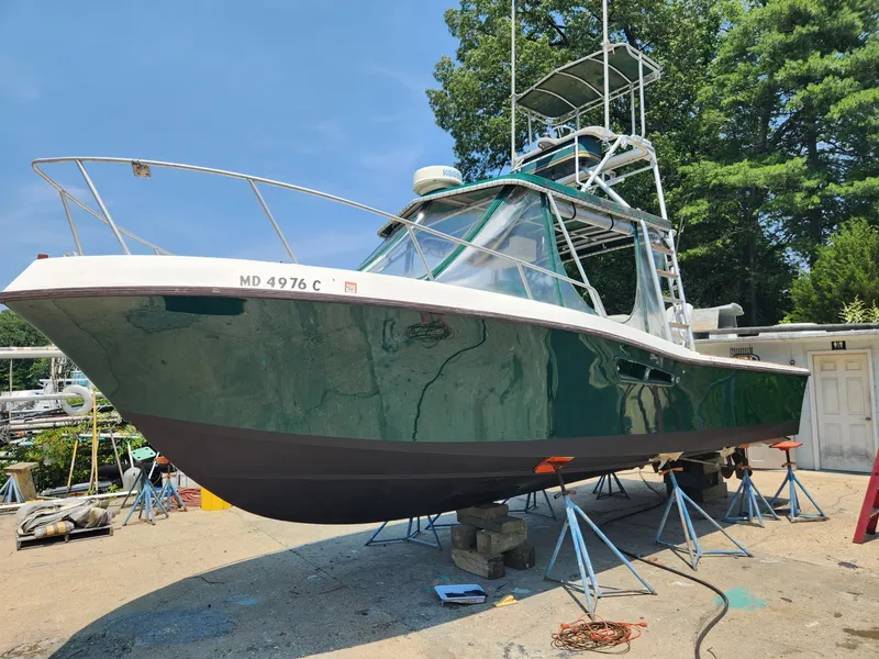 Slide: The Image of A 1989 Mako 286 boat on stands. It features a green hull and a superstructure with radar. - 0