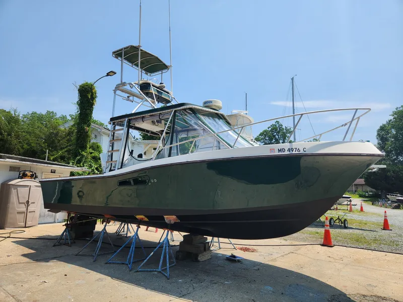 Slide: The Image of A 1989 Mako 286 boat on dry dock. It features a green hull and elevated helm. - 1