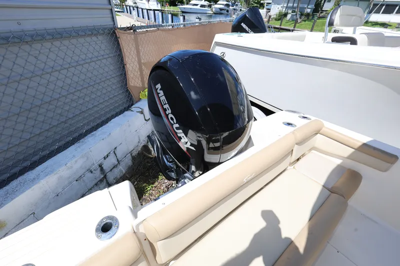 Slide: The Image of 2023 Scout 210 Dorado boat with Mercury outboard motor, docked near a fence. - 22