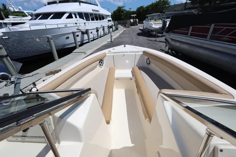 Slide: The Image of 2023 Scout 210 Dorado boat interior with beige seating, docked near other vessels. - 13