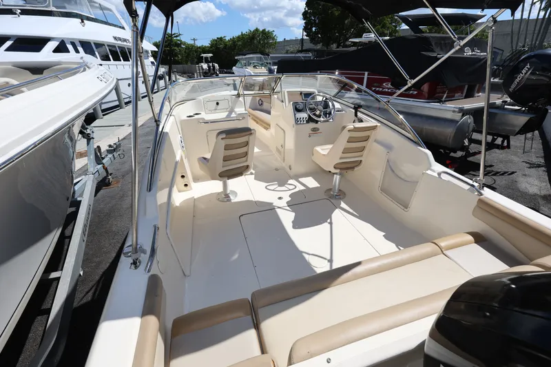 Slide: The Image of 2023 Scout 210 Dorado boat interior with seating and steering wheel, docked outdoors. - 8