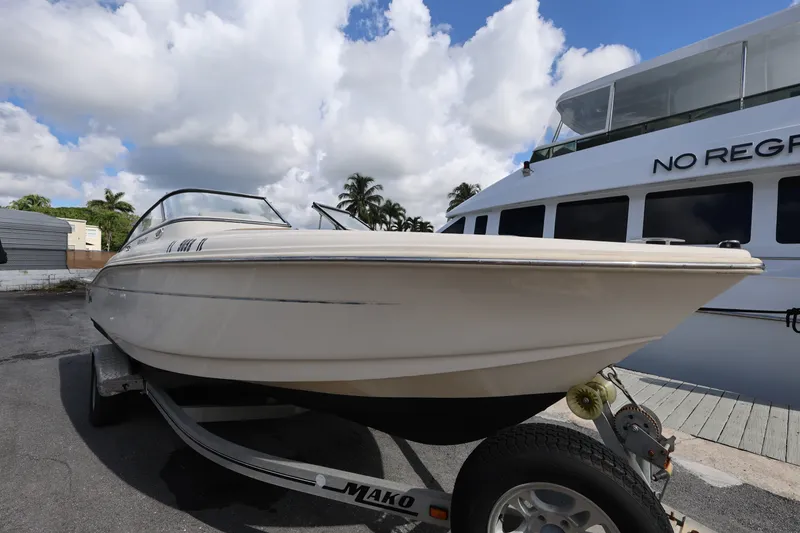 Slide: The Image of 2023 Scout 210 Dorado boat on trailer, parked near a larger vessel. - 7