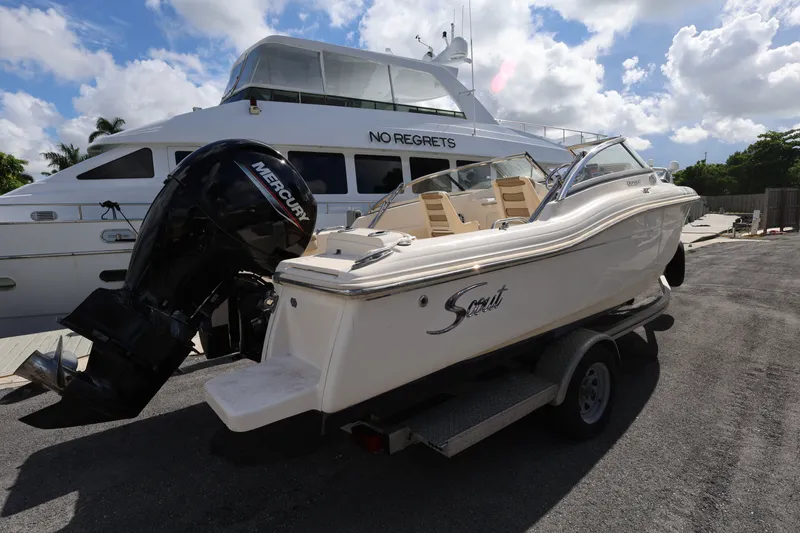 The Image of 2023 Scout 210 Dorado boat on trailer, parked beside a larger yacht. - 0