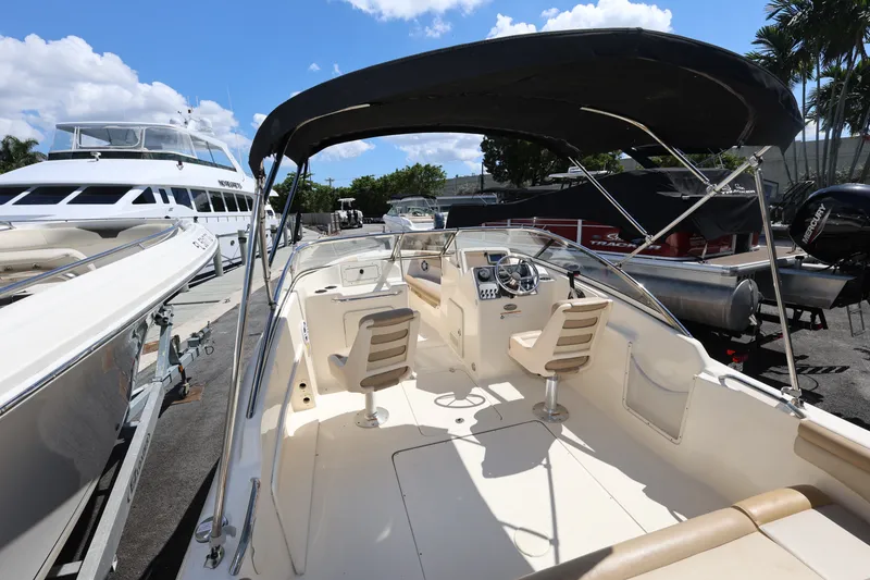 Slide: The Image of 2023 Scout 210 Dorado boat with canopy, docked alongside other vessels under a clear blue sky. - 9