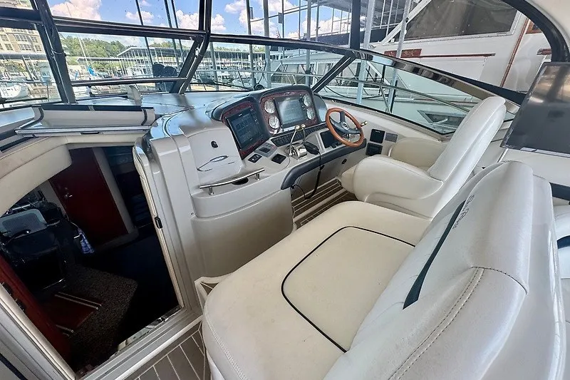 Slide: The Image of 2005 Sea Ray 390 Sundancer cockpit with modern controls and comfortable seating at a marina. - 22