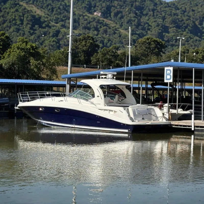 Slide: The Image of A 2005 Sea Ray 390 Sundancer docked in calm waters, surrounded by wooded hills. - 0