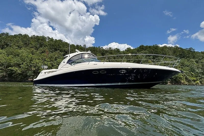 Slide: The Image of 2005 Sea Ray 390 Sundancer yacht on a serene lake with lush green backdrop. - 2