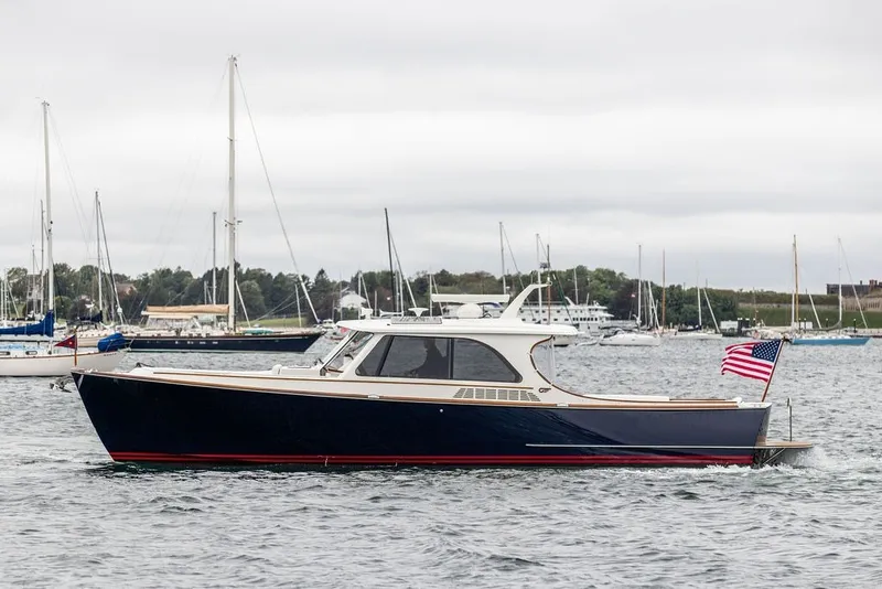Slide: The Image of 2026 Hinckley Picnic Boat 39 cruising on a calm harbor with sailboats in the background. - 4