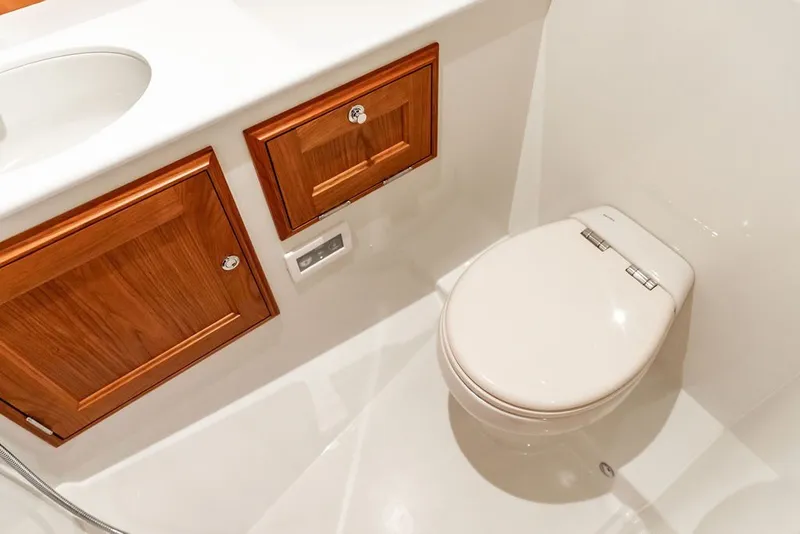 Slide: The Image of Hinckley Picnic Boat 39 (2026) bathroom with wooden cabinets and modern toilet. - 33
