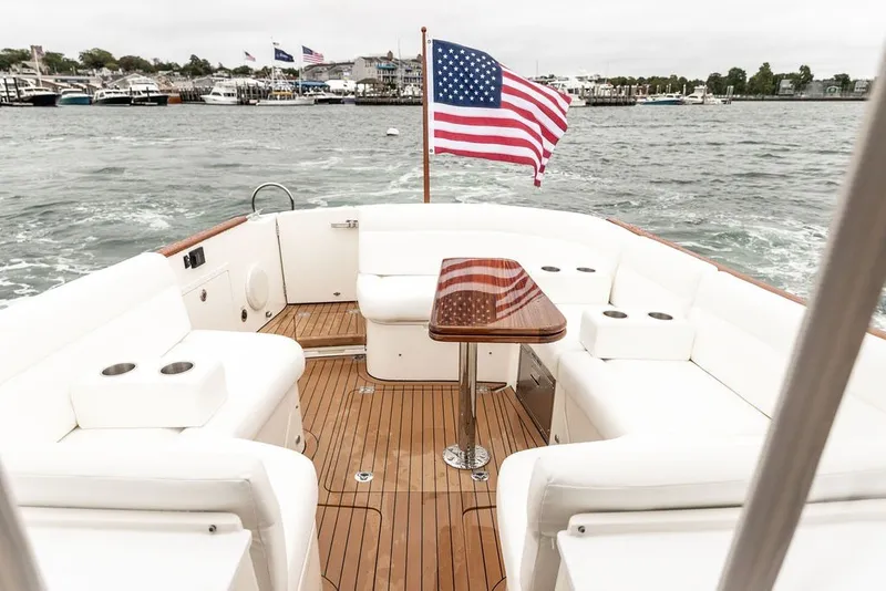 Slide: The Image of 2026 Hinckley Picnic Boat 39 with American flag, elegant seating, and wooden deck on the water. - 6