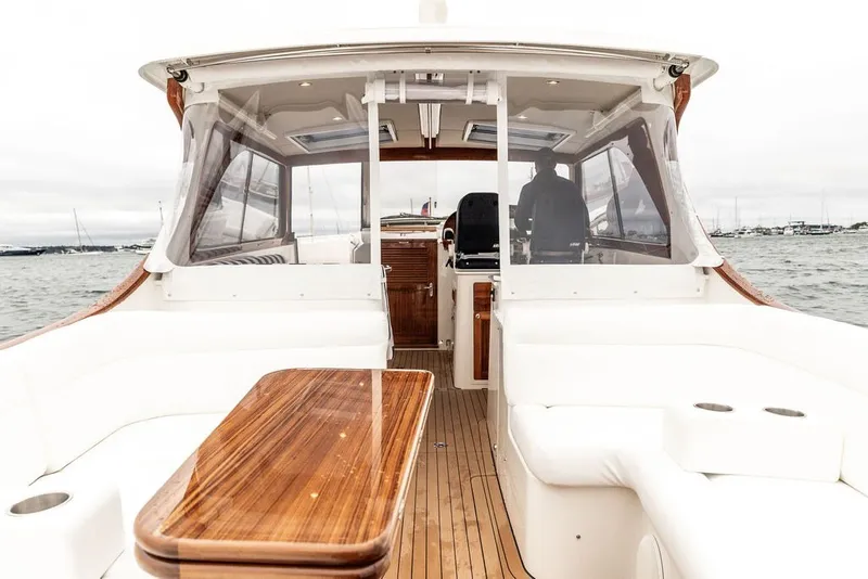 Slide: The Image of 2026 Hinckley Picnic Boat 39 interior with elegant wood and white seating on the water. - 8