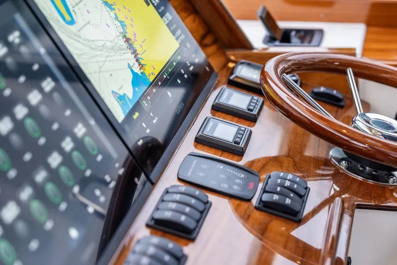 Slide: The Image of 2026 Hinckley Picnic Boat 39 dashboard with navigation screen and wooden steering wheel. - 23