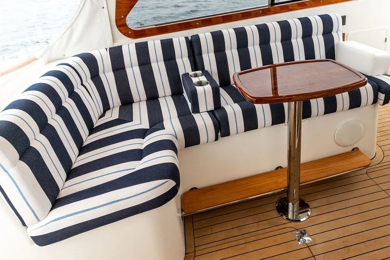 Slide: The Image of Luxury seating area on 2026 Hinckley Picnic Boat 39 with striped cushions and wooden table. - 15