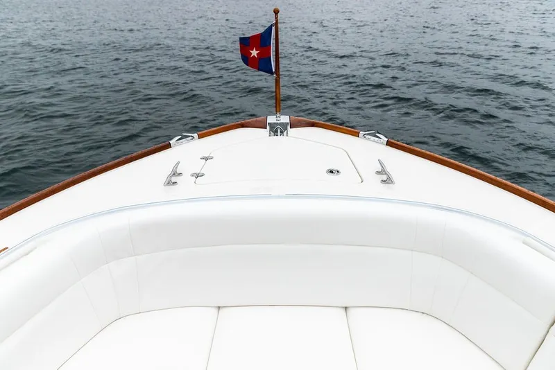 Slide: The Image of Bow view of 2026 Hinckley Picnic Boat 39 with elegant white seating and nautical flag. - 19
