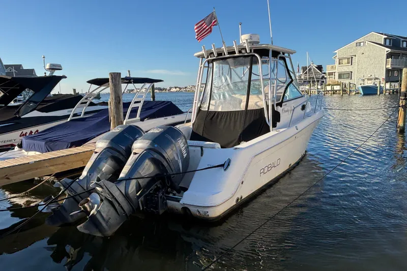 Slide: The Image of 2004 Robalo R245 Walkaround boat docked with dual Yamaha engines and American flag. - 2