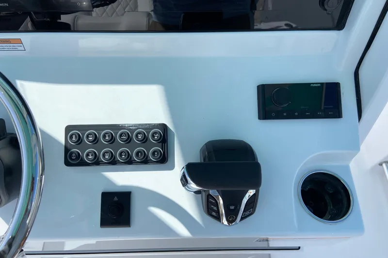Slide: The Image of La imagen muestra el timón de un barco Sportsman Open 232 Center Console. Se ven el volante, el panel de interruptores, el acelerador y el portavasos. - 13