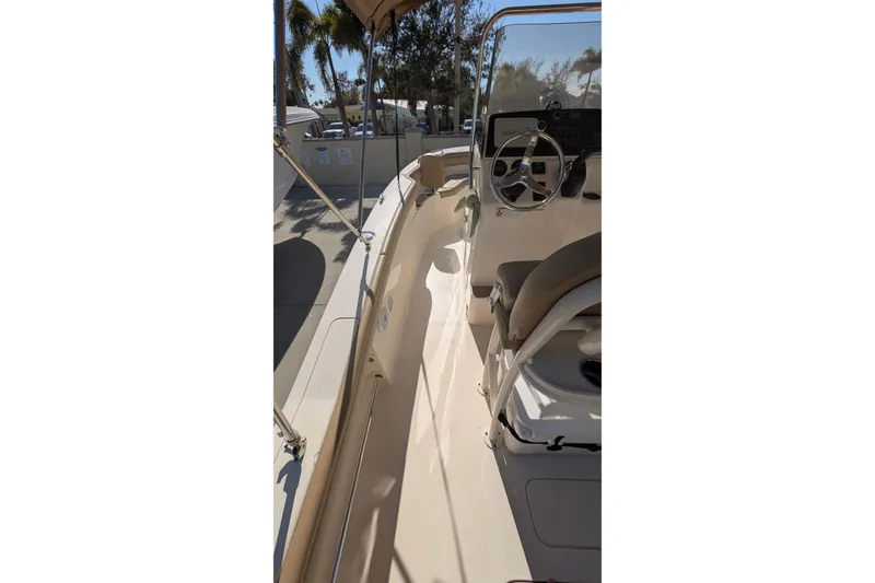 Slide: The Image of 2019 Scout 215 XSF boat interior with steering wheel and seating, under sunny skies. - 26