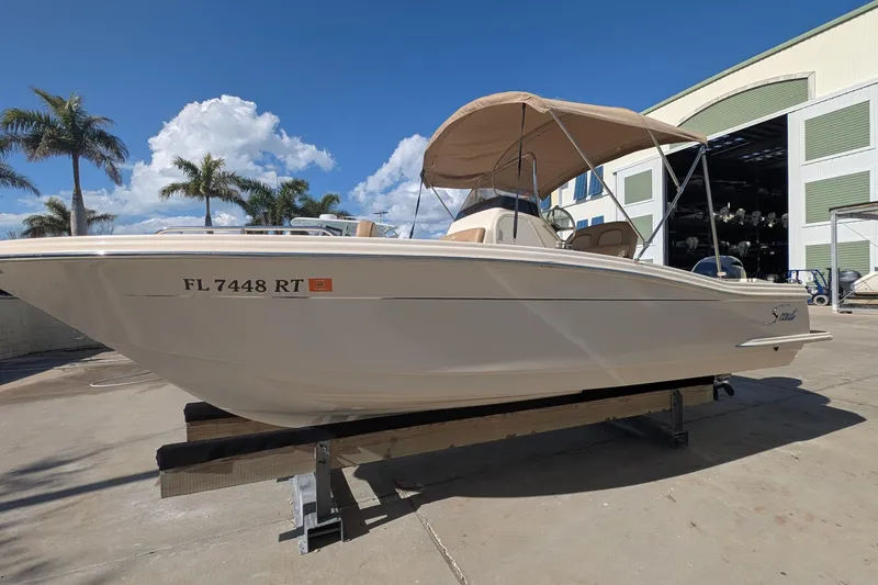 Slide: The Image of 2019 Scout 215 XSF boat on display with palm trees and blue sky background. - 0