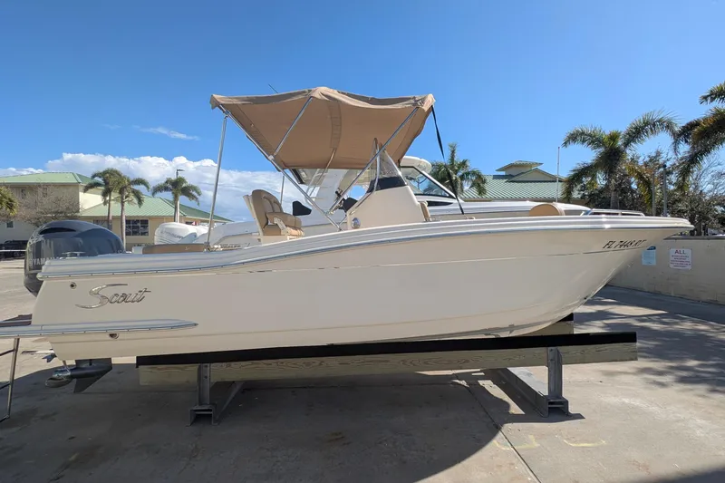 Slide: The Image of 2019 Scout 215 XSF boat with canopy, parked outdoors under clear blue sky. - 1