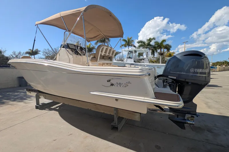 Slide: The Image of 2019 Scout 215 XSF boat with Yamaha engine, parked outdoors under clear sky. - 6