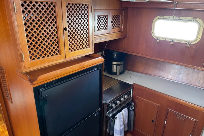 Slide: The Image of 1985 CHB 42 boat kitchen with wooden cabinets, stove, and window. - 40