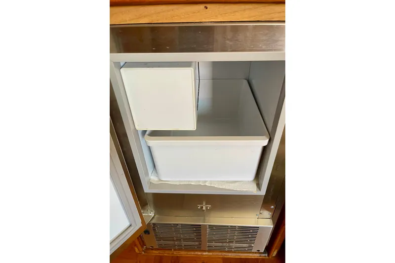 Slide: The Image of Open refrigerator compartment on a 1985 CHB 42 boat, featuring a white storage bin. - 36