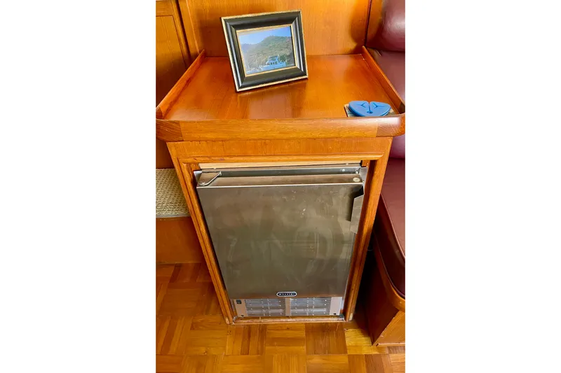 Slide: The Image of Wooden interior of 1985 CHB 42 boat with a compact fridge and framed photo. - 35