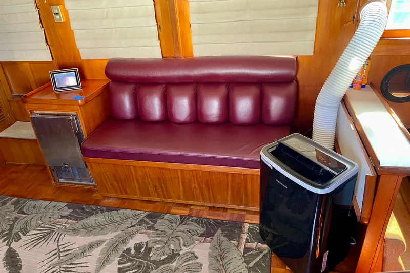 Slide: The Image of Interior of a 1985 CHB 42 boat with maroon seating and portable air conditioner. - 25