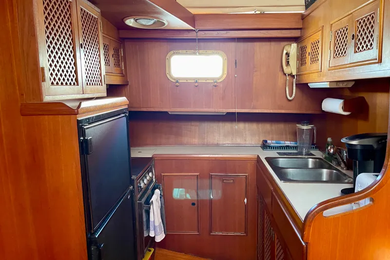 Slide: The Image of 1985 CHB 42 yacht kitchen with wooden cabinets, stove, sink, and window. - 46