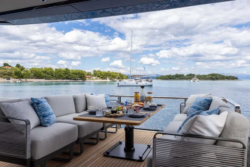 Slide: The Image of Luxury yacht deck with dining setup, overlooking serene waters and sailboats. Absolute Navetta Co Ownership 2026. - 30