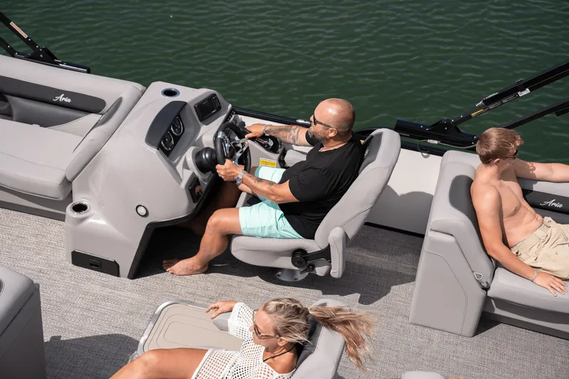 Slide: The Image of A man steers a Barletta Aria 22 QC boat while two people relax. - 2