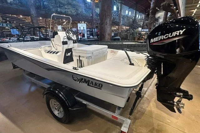 Slide: The Image of 2027 Mako Pro Skiff 15 CC boat with Mercury engine on display indoors. - 2