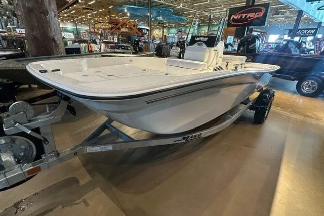 Slide: The Image of 2027 Mako Pro Skiff 15 CC boat displayed indoors on a trailer. - 3