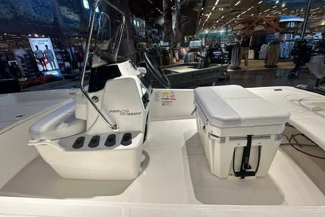 Slide: The Image of 2027 Mako Pro Skiff 15 CC boat interior with seating and storage in showroom. - 5