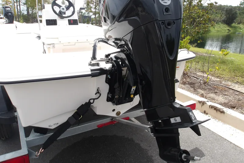 Slide: The Image of 2027 Mako Pro Skiff 15 CC boat with outboard motor, parked near a lake. - 3