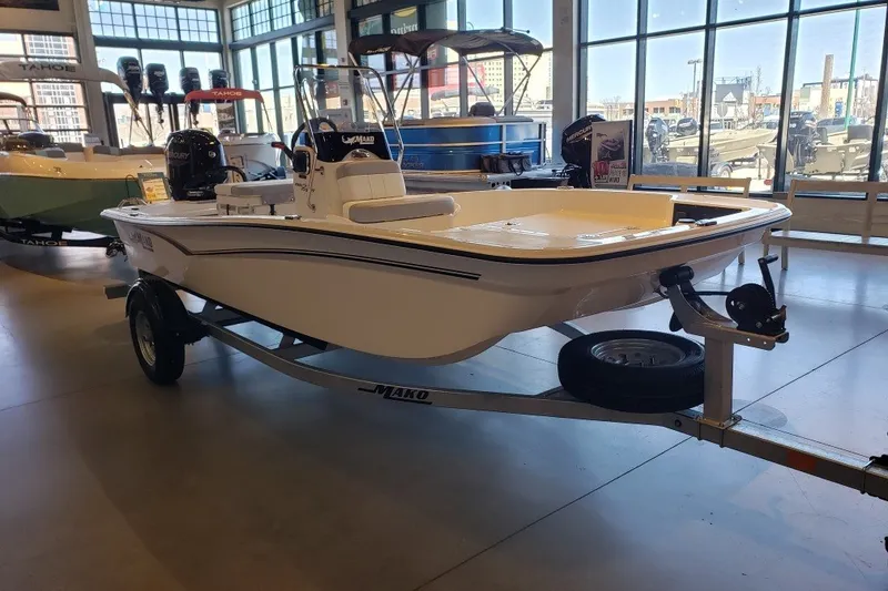 Slide: The Image of 2027 Mako Pro Skiff 15 CC boat displayed in a showroom on a trailer. - 2