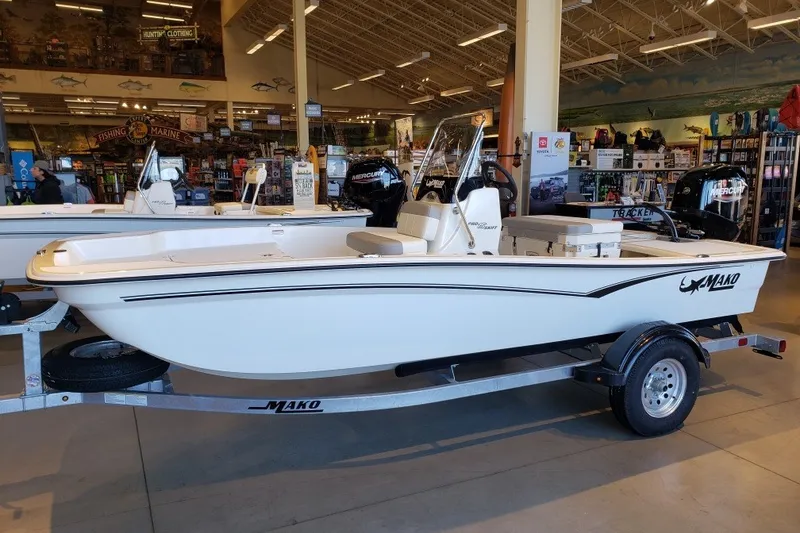 Slide: The Image of 2027 Mako Pro Skiff 15 CC boat displayed in a showroom on a trailer. - 1